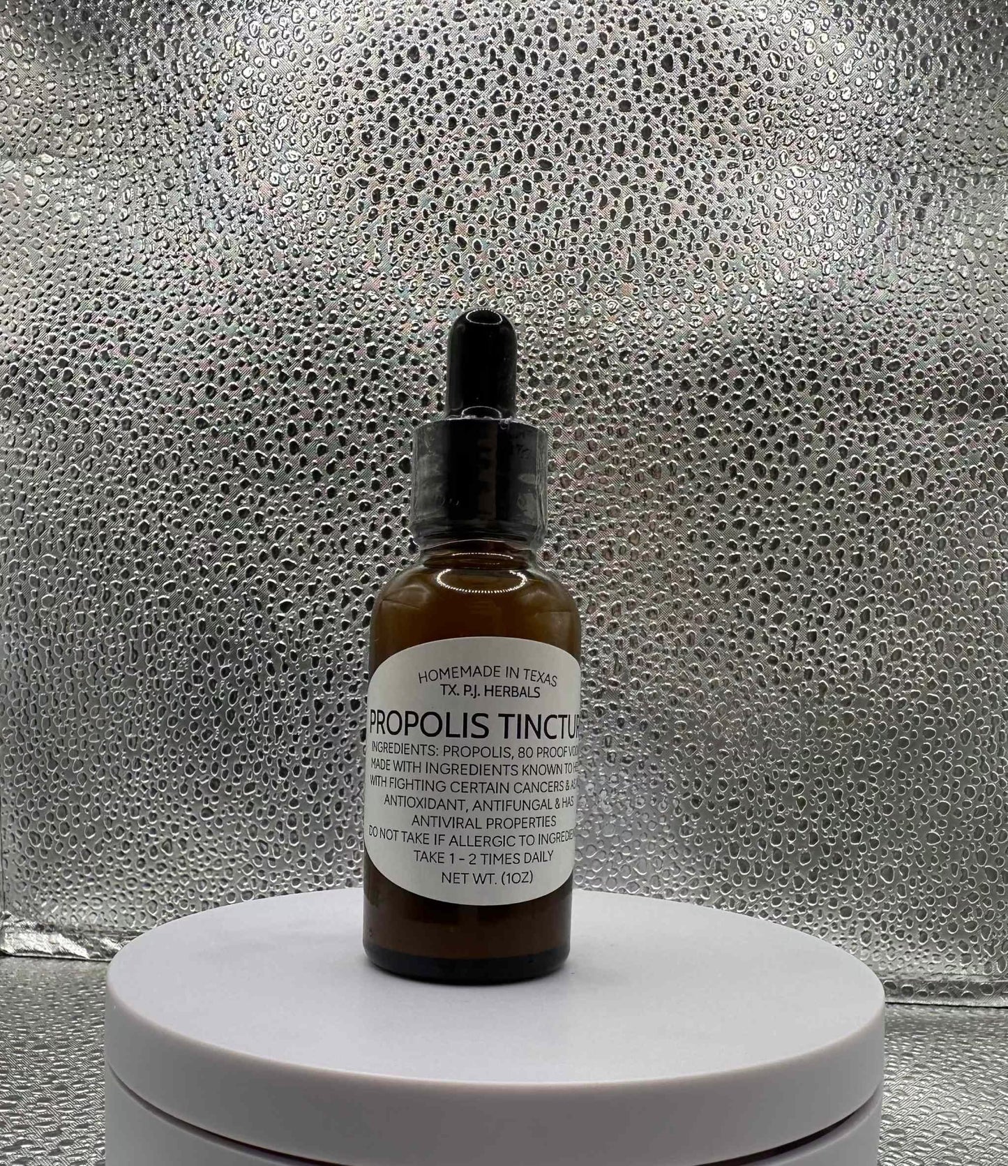 Bottle of All-Natural Propolis Tincture with wooden dropper and honeycomb background